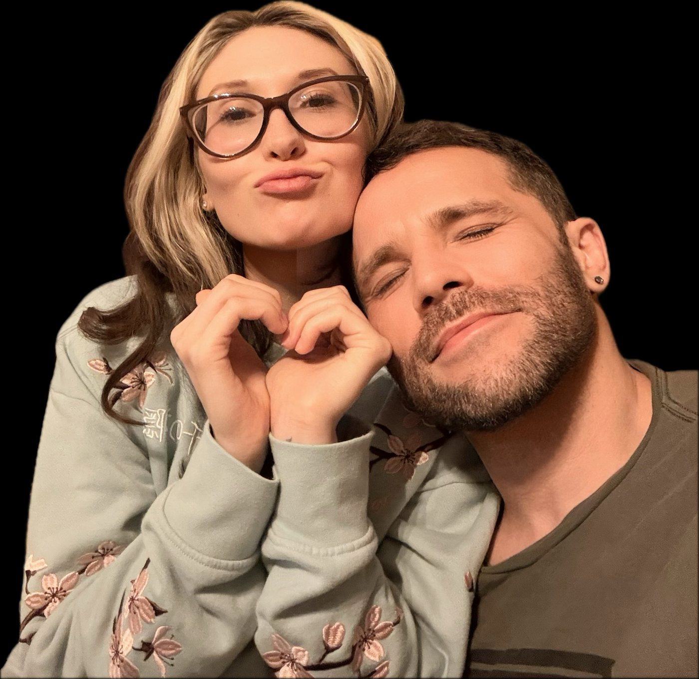 Renee making a heart with her hands while Ludwig leans on her shoulder